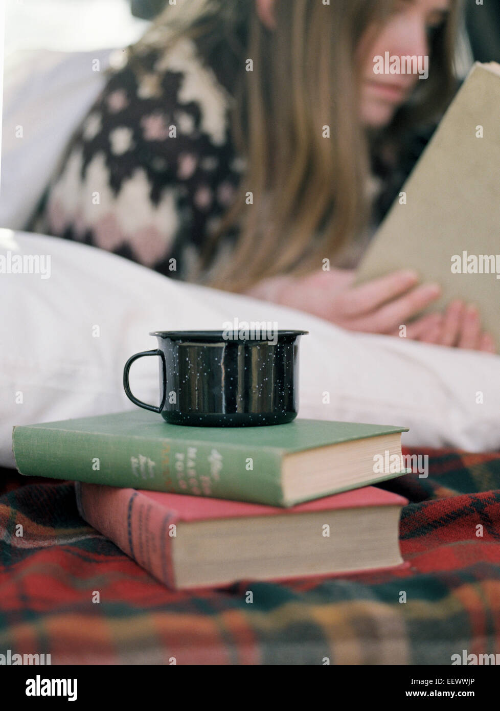Junge Frau ein Buch, eine Tasse steht auf zwei Bücher zu lesen. Stockfoto