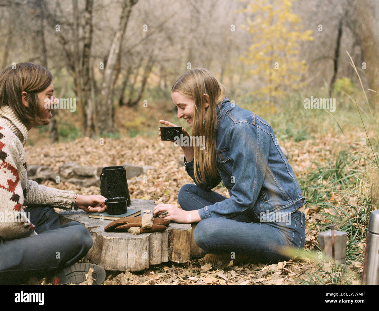 Lächelnde paar sitzen auf dem Boden in einem Wald, Kaffee zu trinken. Stockfoto