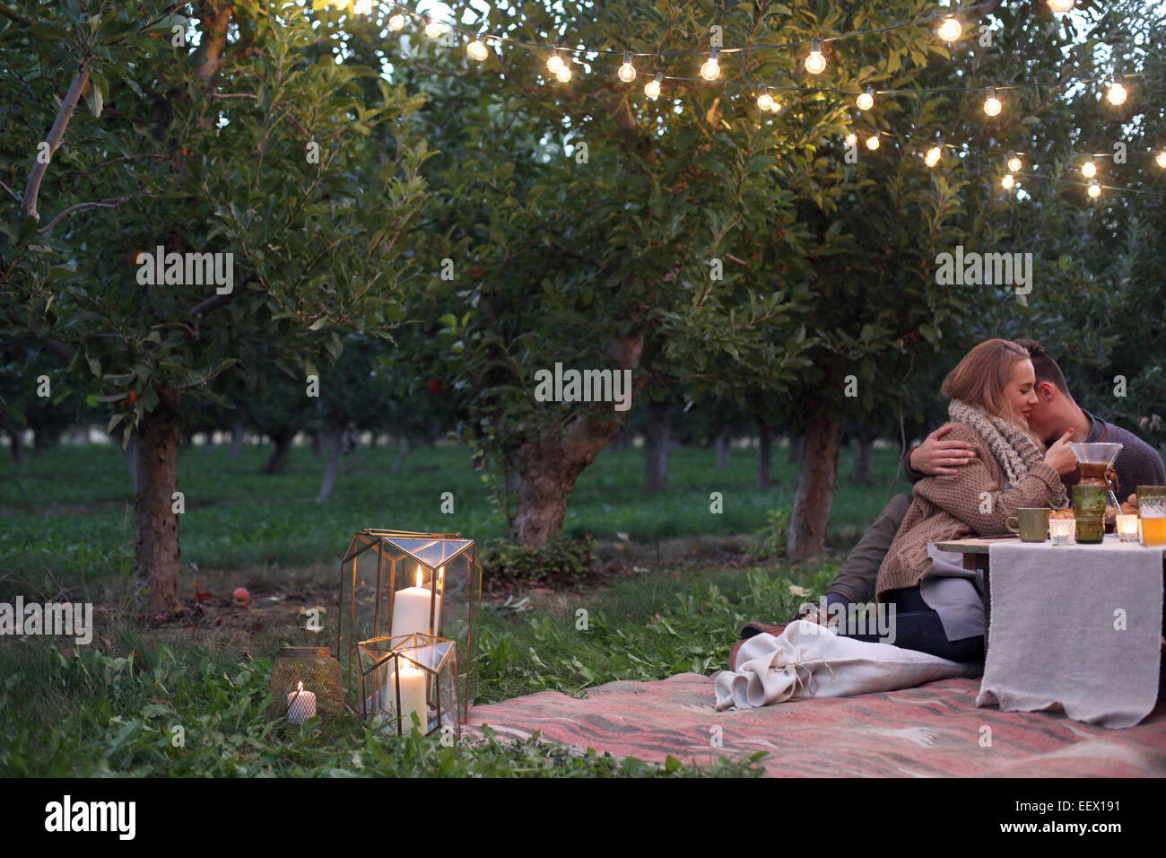 Apfelplantage. Paar auf dem Boden sitzend Stockfoto