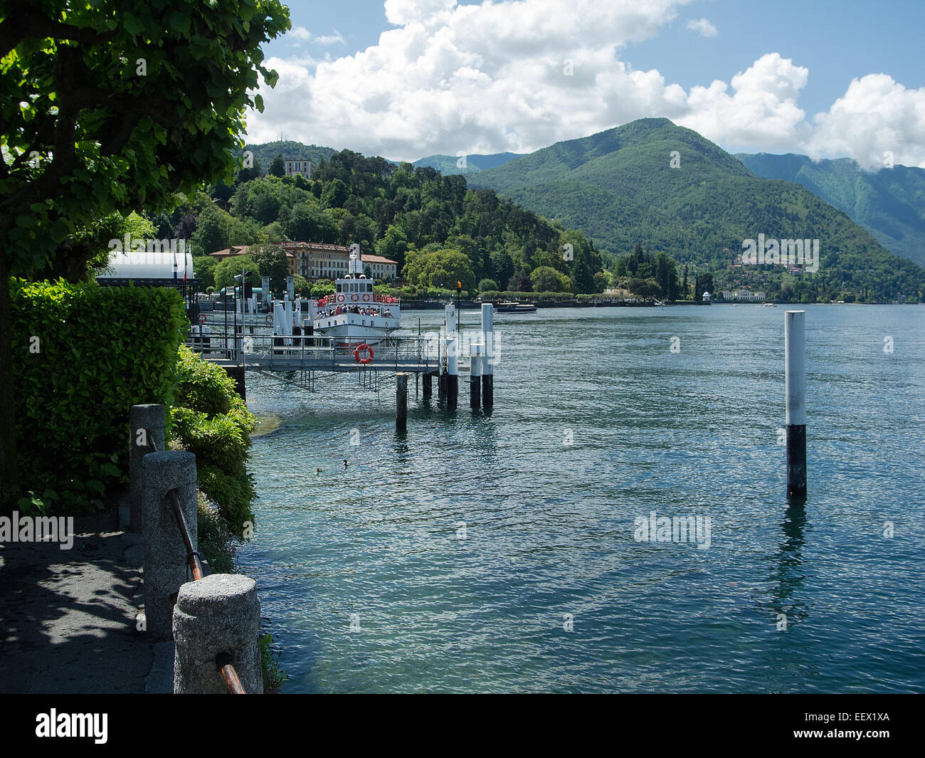 Landeplatz in Bellagio am See des Comer Sees in Italien mit einer Fähre und einer baumgesäumten Bergkulisse im Frühsommer Stockfoto