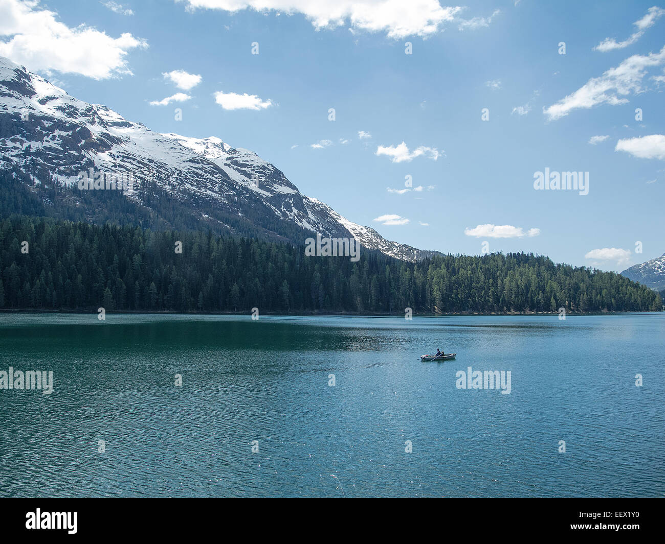 Kleines Boot mitten im See mit schneebedeckten Bergen und blauem Himmel in  St. Moritz in der Schweiz Stockfotografie - Alamy