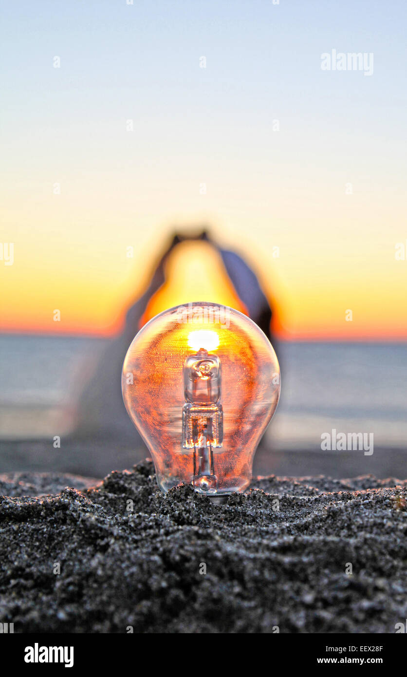 Glühbirne auf einem sandigen Strand bei Sonnenaufgang mit Braut und  Bräutigam küssen im Hintergrund Stockfotografie - Alamy