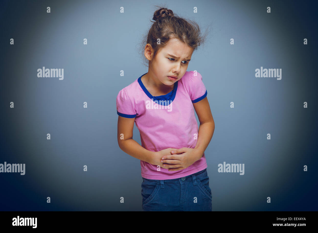 Mädchen Kind Bauchschmerzen auf grauem Hintergrund cross-Entwicklung Stockfoto