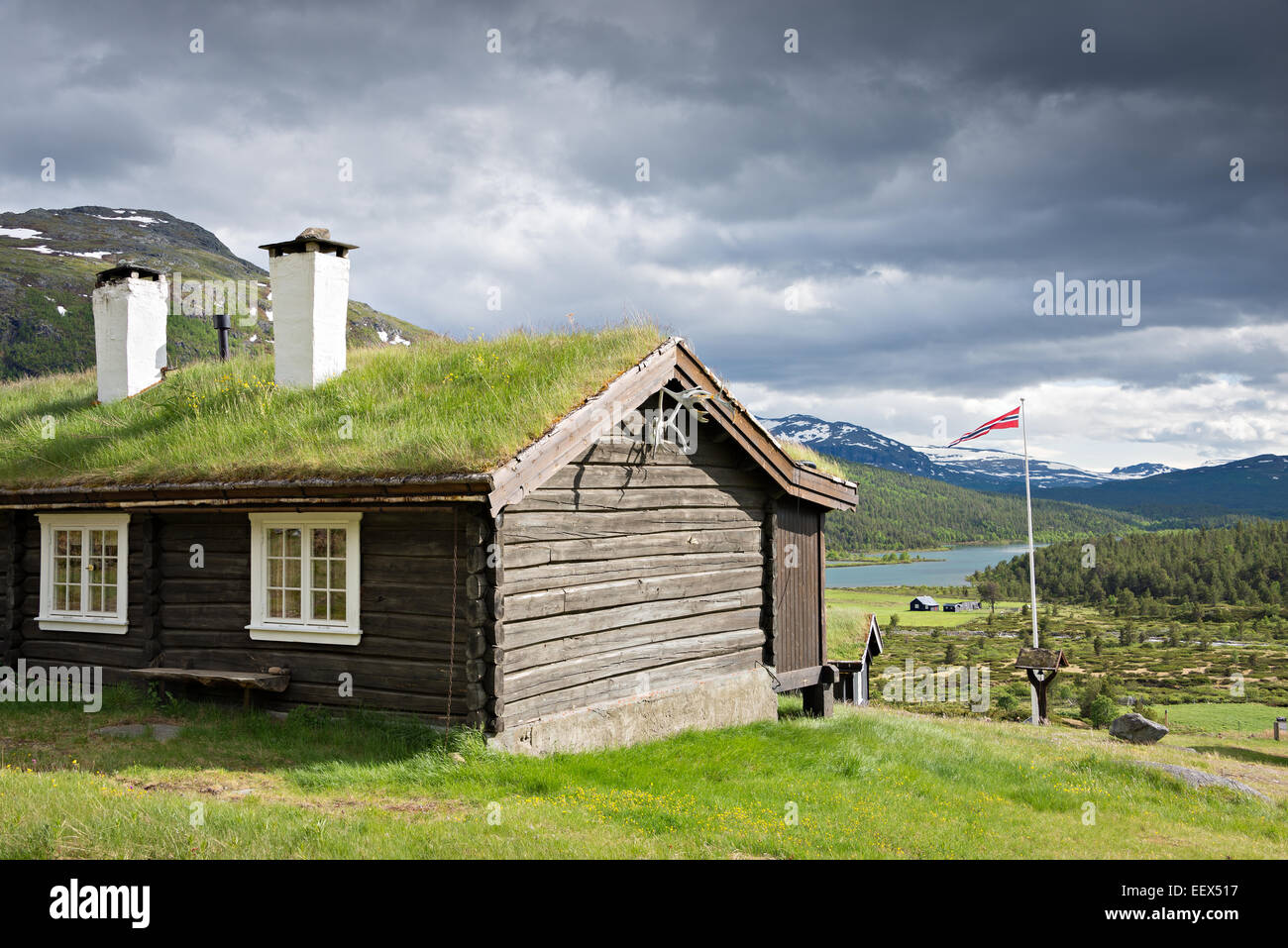 Ein Sod-Dach-Blockhaus mit Rasen auf der Oberseite und zwei Kamine mit Blick über einen See in einem Tal im Nationalpark Jotunheimen, Norwegen Stockfoto