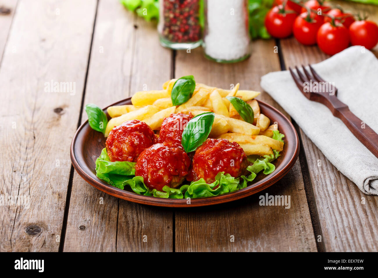 Fleischbällchen in Tomatensauce mit Pommes frites Stockfoto