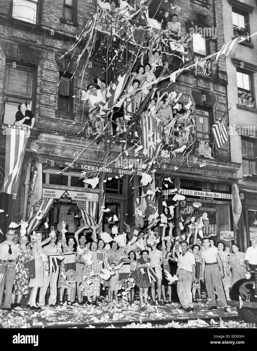 Bewohner von New York "Little Italy" vor 76 Mulberry St., grüßen die Nachricht von der japanischen Akzeptanz der Alliierten Kapitulation mit wehenden Fahnen und ein Regen von Papier, 1945 Stockfoto