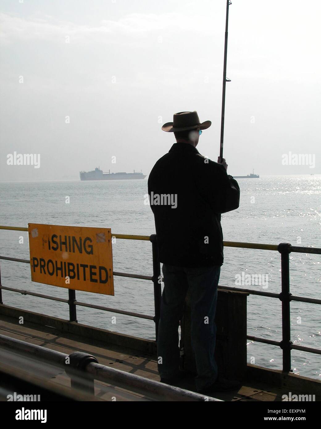 rechtswidrig und illegale Verhalten Mann Angeln gegen Fischerei verboten Schild Vereinigtes Königreich Stockfoto