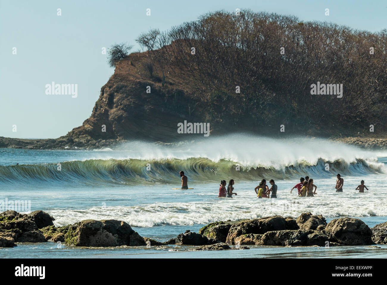 Menschen genießen den Spaß Wellen, die typisch für diese Küste sind; Playa Hermosa, San Juan del Sur, Provinz Rivas, Nicaragua Stockfoto