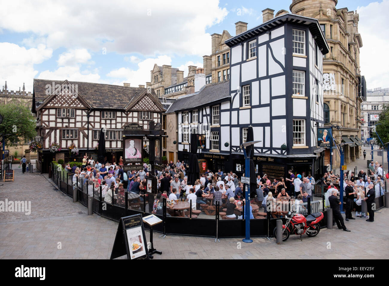 Besetzt Das alte Fachwerkhaus aus dem 16. Jahrhundert Wellington Inn 1552 städtischen Pub mit einer Menge von Menschen in den Biergarten. Manchester, England, Großbritannien, Großbritannien Stockfoto