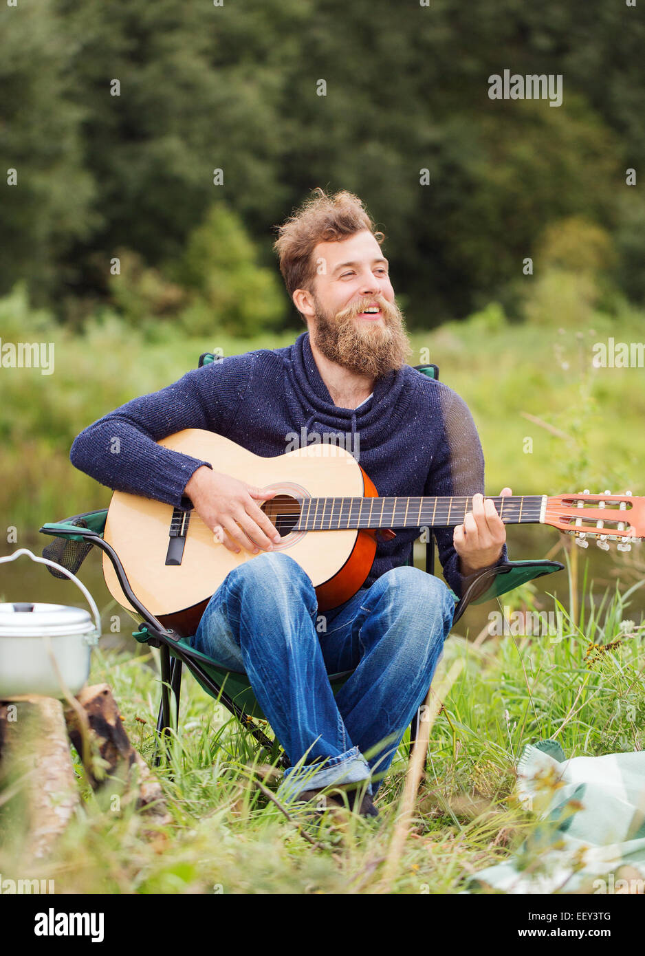 lächelnder Mann mit Gitarre und Dixie im camping Stockfoto