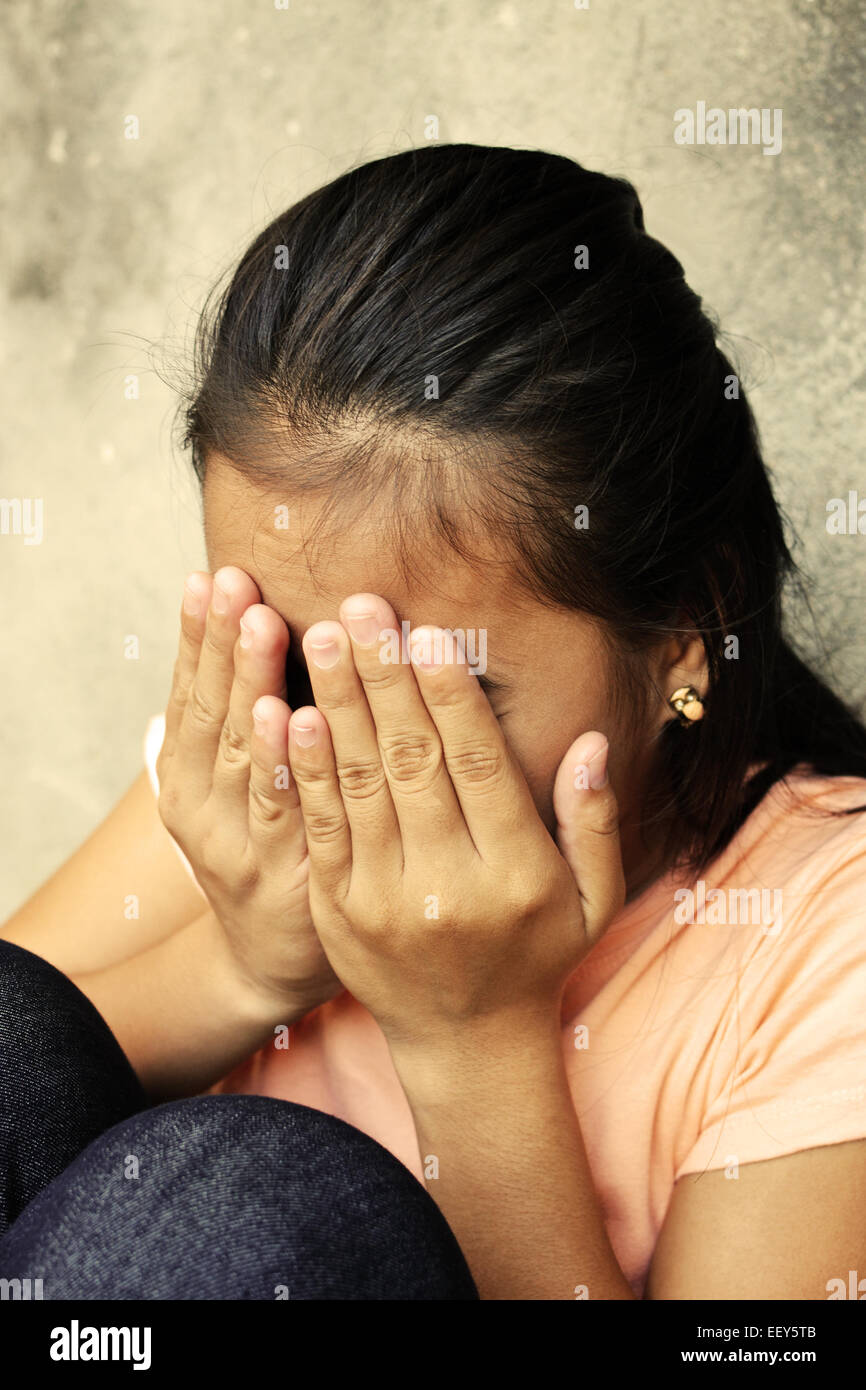 Teenager bedeckte ihr Gesicht mit den Händen in einem verlassenen Ort weint Stockfoto