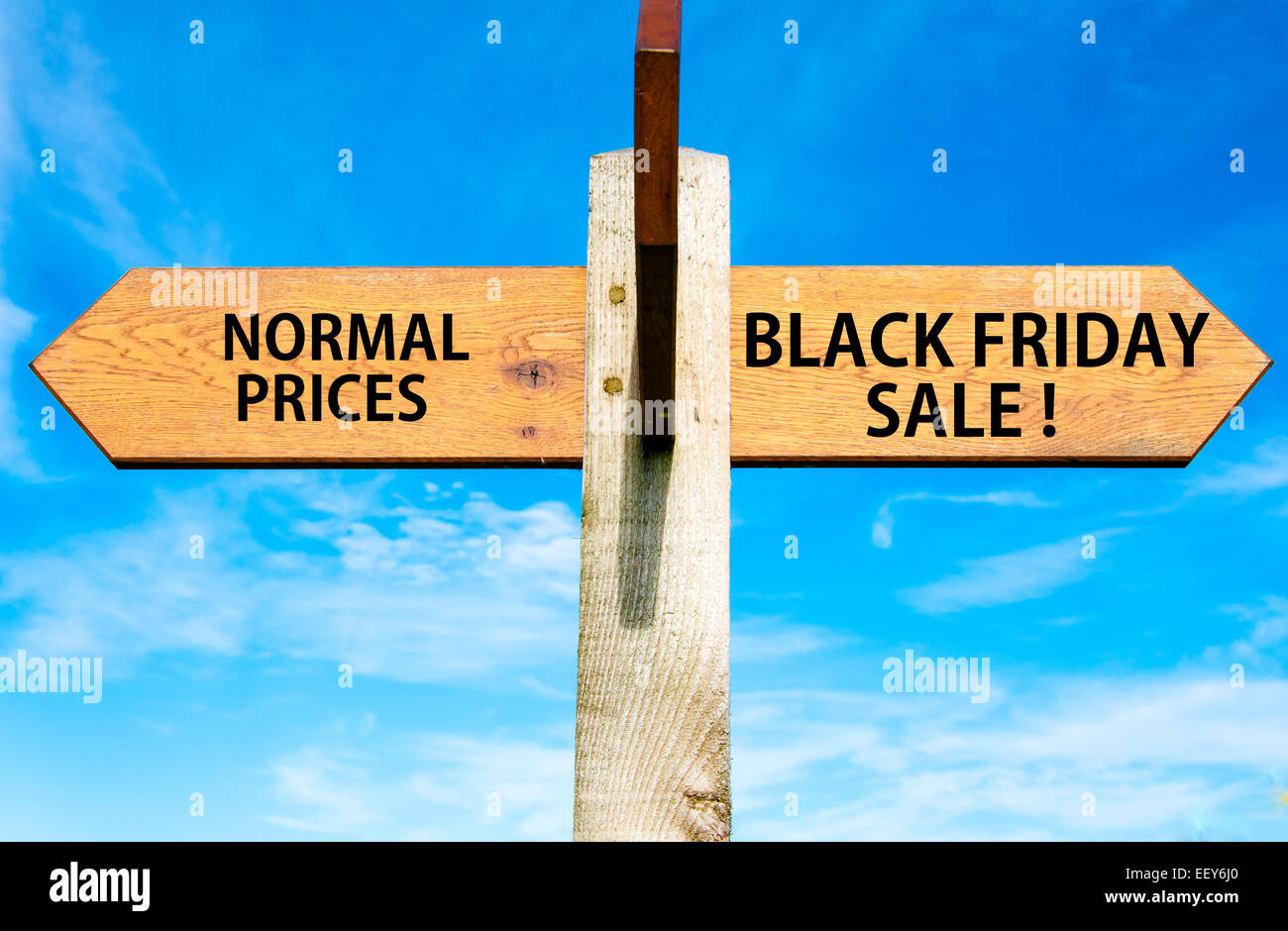 Wegweiser aus Holz mit zwei entgegengesetzte Pfeile über klaren, blauen Himmel, normale Preise im Vergleich zu Black Friday Verkauf Nachrichten, konzeptionelle Vertrieb Stockfoto
