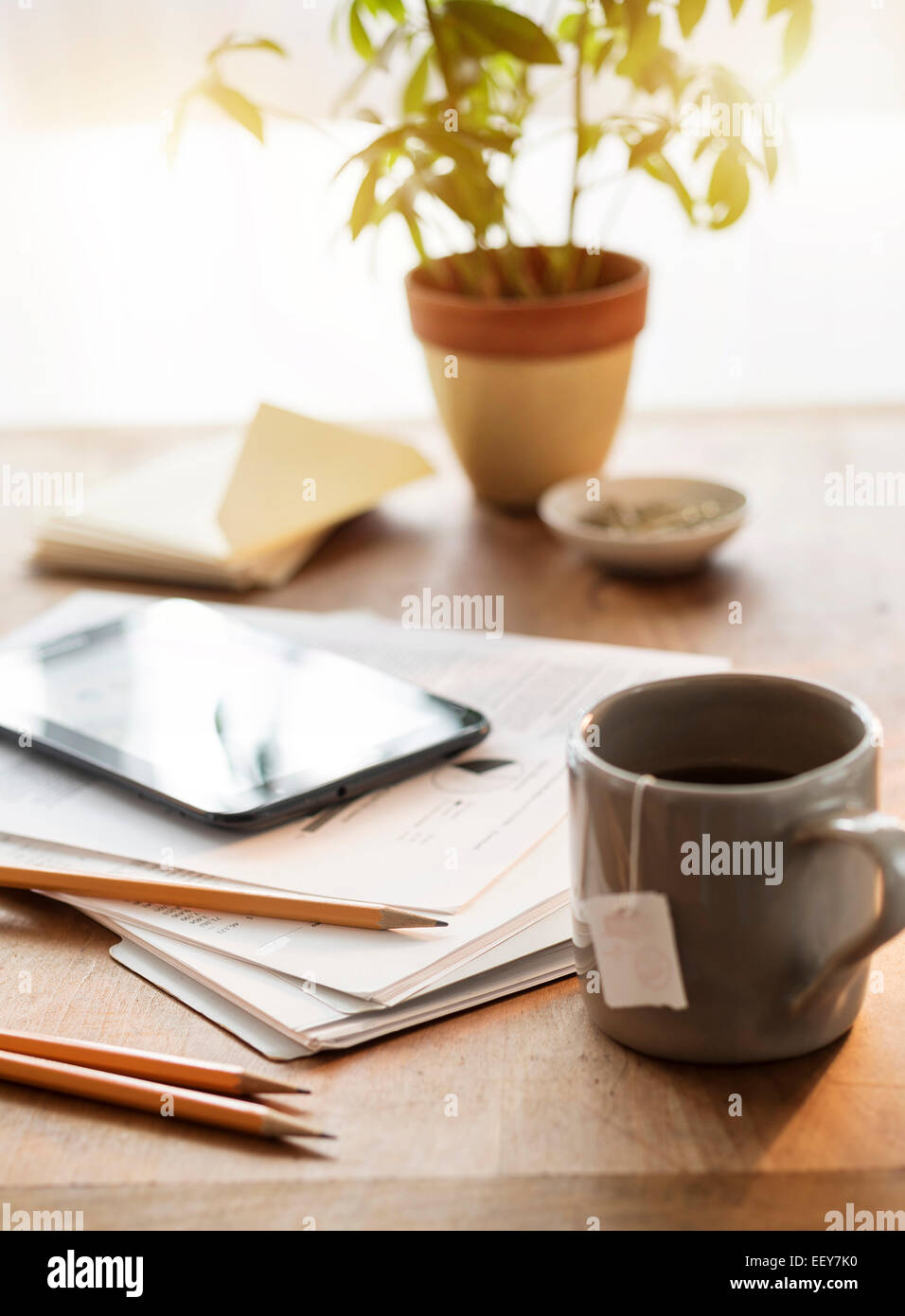 Nahaufnahme von Schreibtisch mit Becher Papiere Tablet und Bleistifte Stockfoto