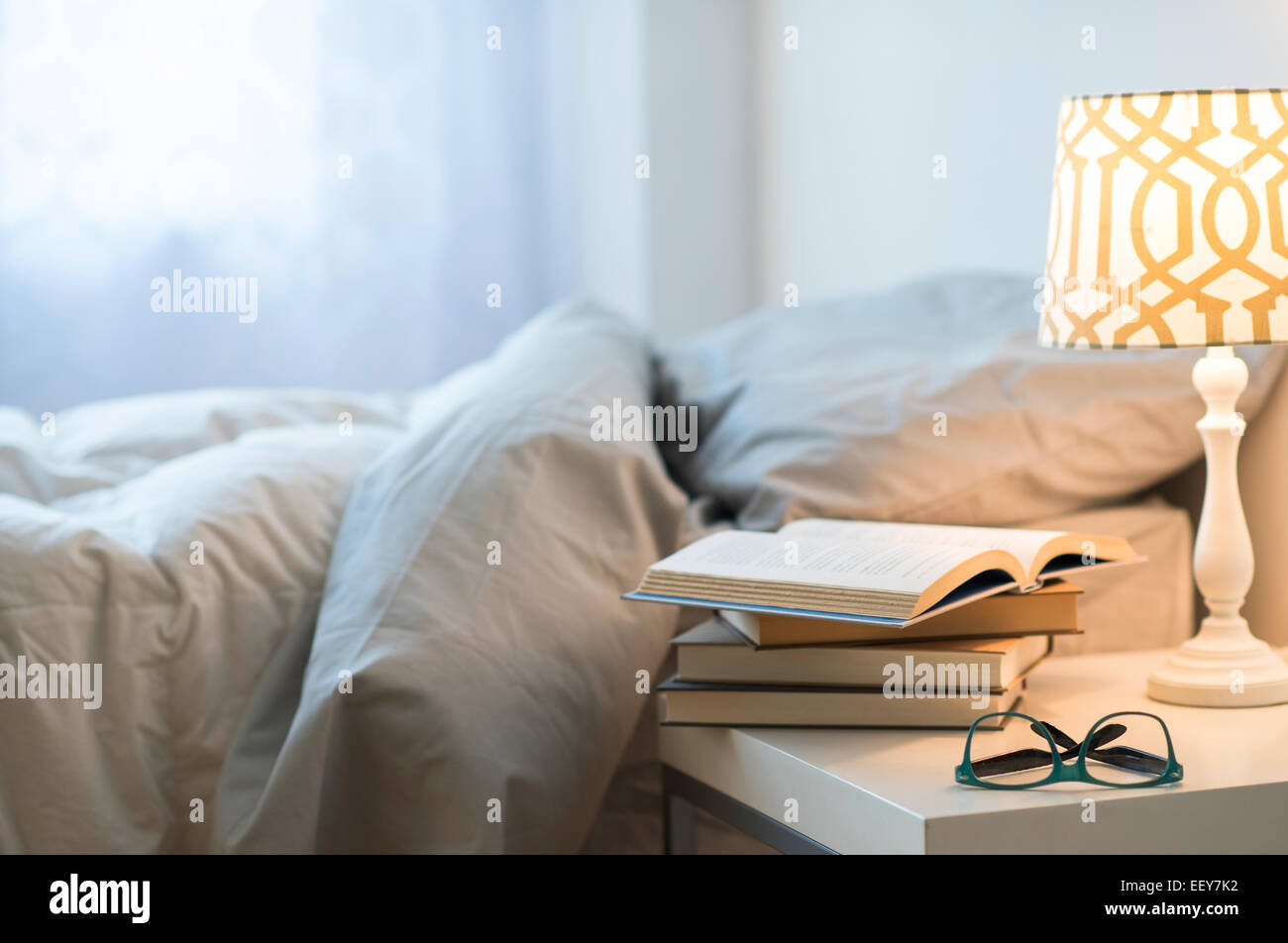 Bett mit Lampe, Bücher und Gläser auf den Nachttisch Stockfoto
