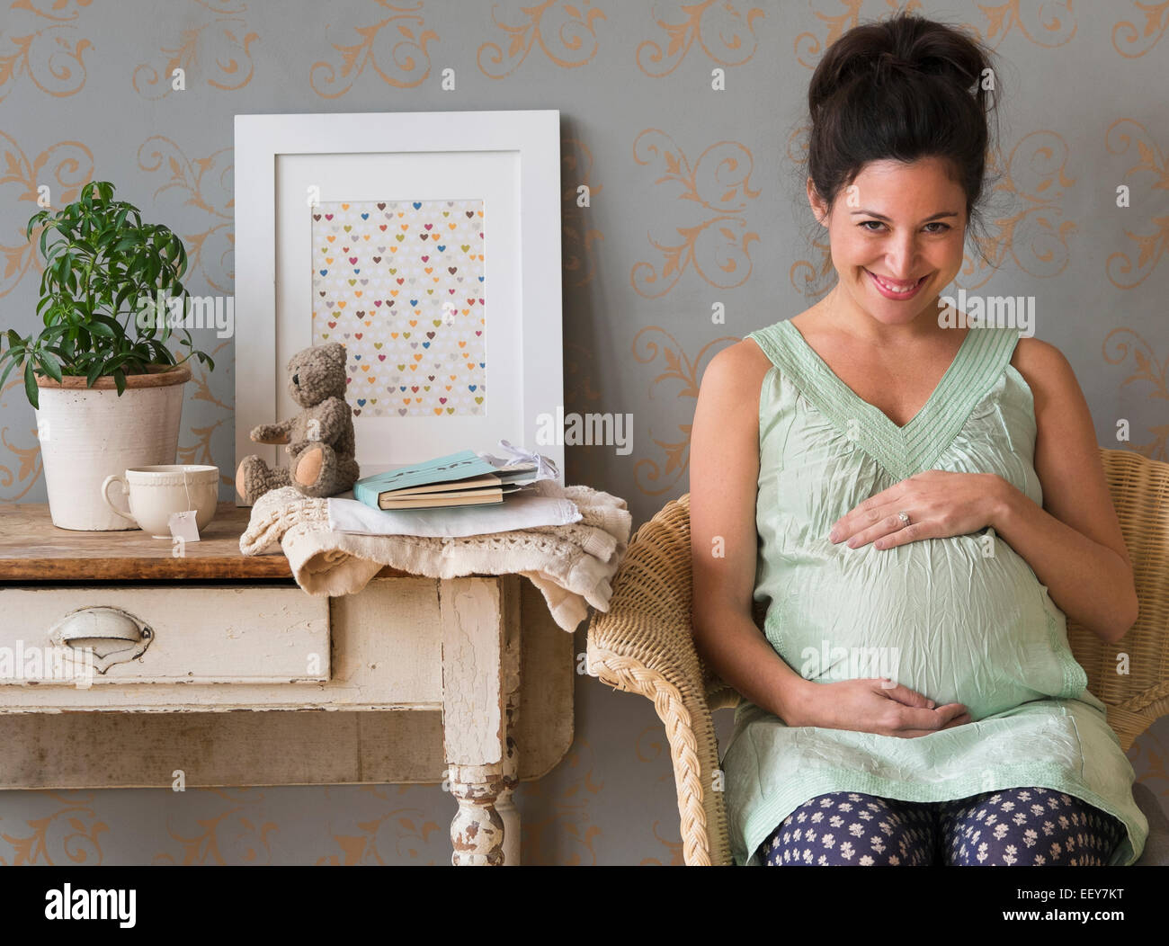 Schwangere Frau sitzen auf Stuhl, berühren, Bauch Lächeln Stockfoto