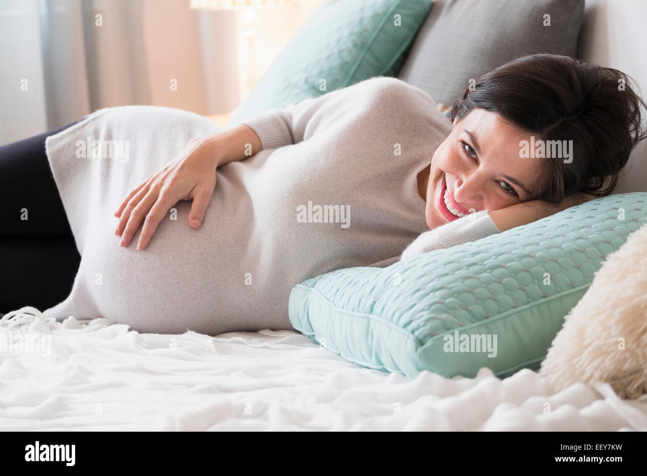 Schwangere Frau im Bett lächelnd Stockfoto