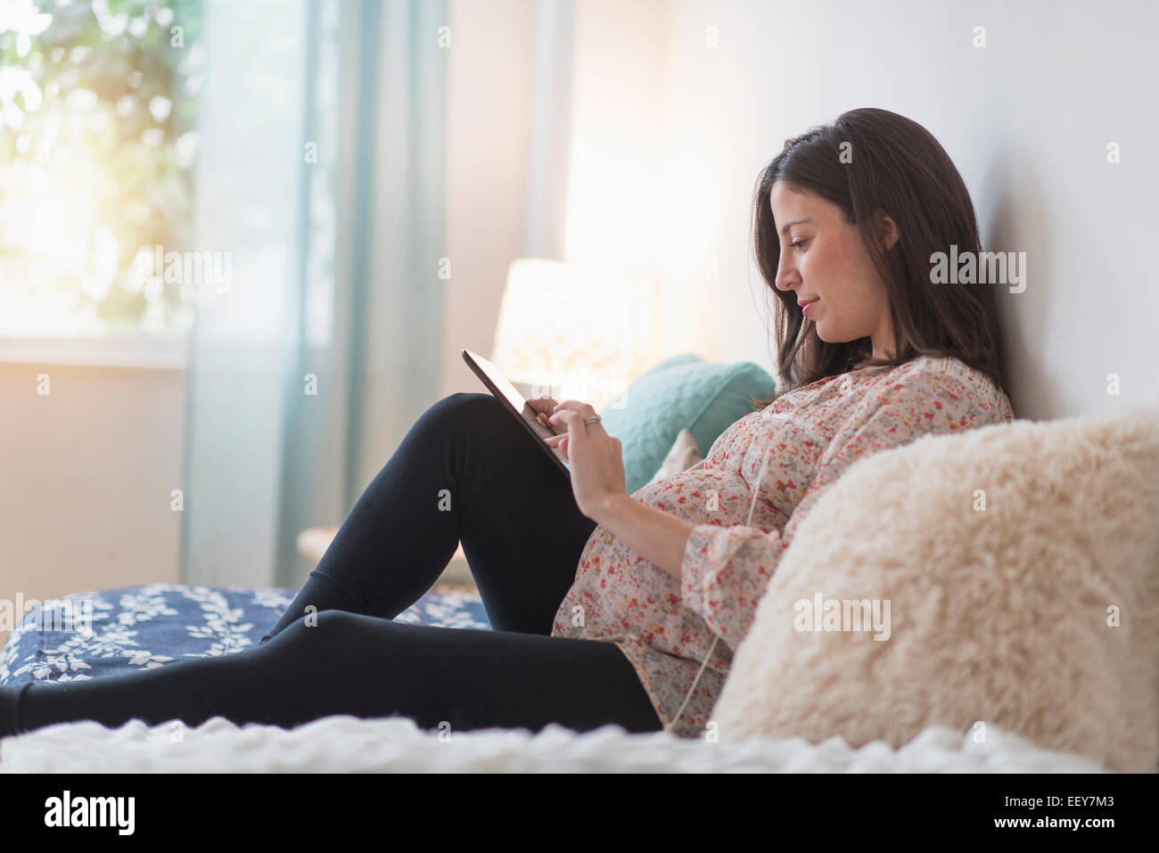 Schwangere Frau sitzen auf Bett mit tablet Stockfoto