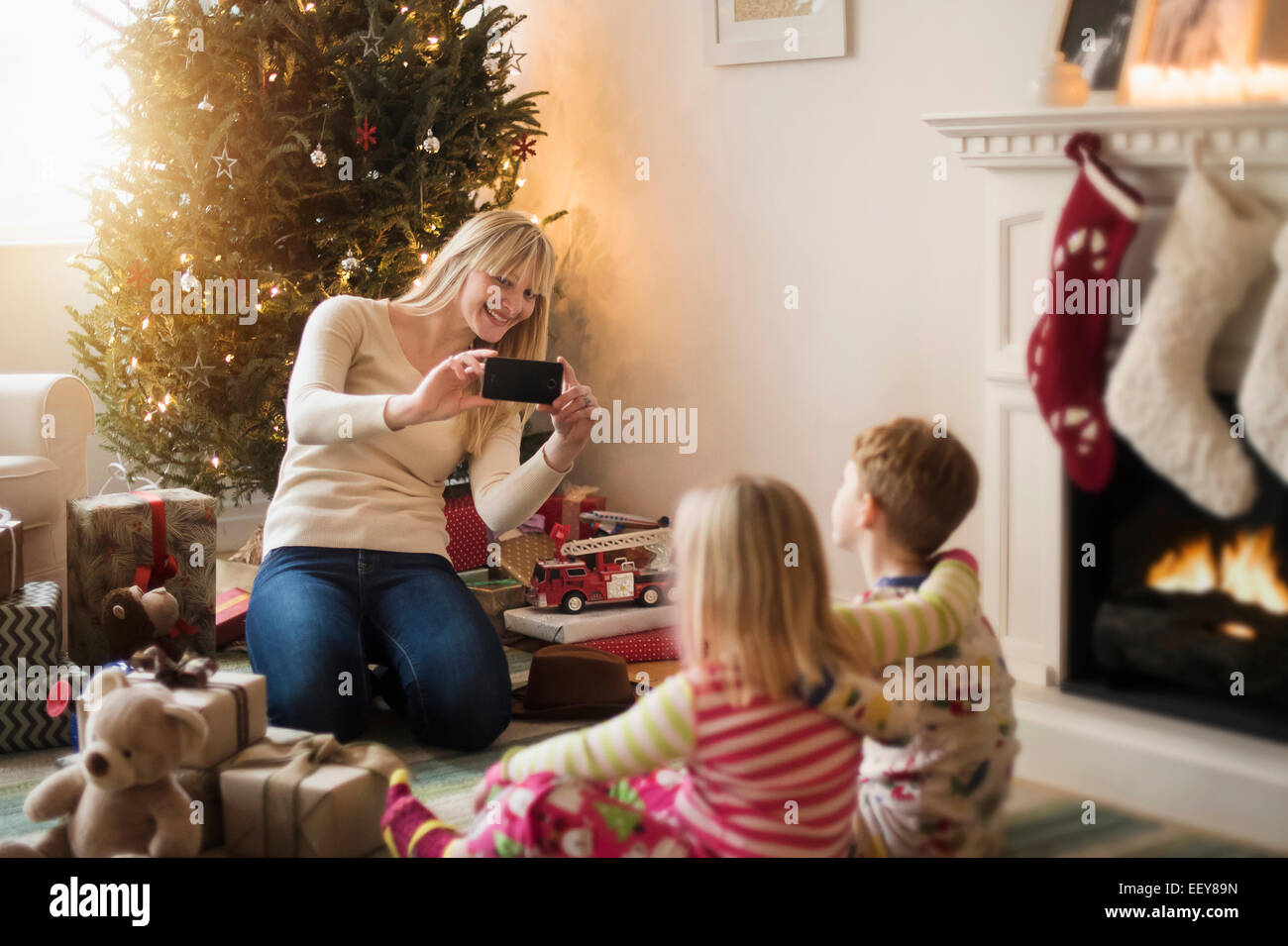 Mutter mit Kinder (4-5, 6 und 7) Eröffnung Weihnachtsgeschenke und fotografieren Stockfoto