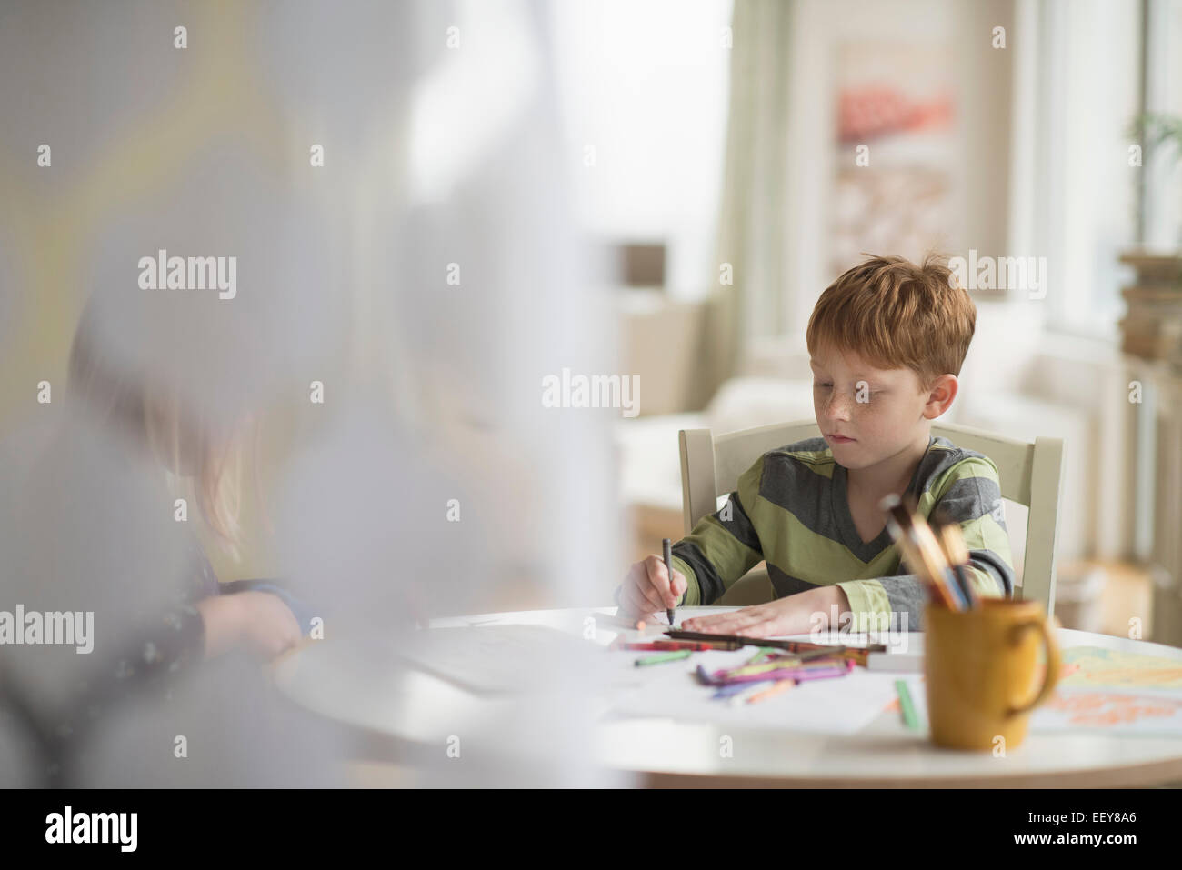 Junge (6-7) sitzen und zeichnen im Familienzimmer Stockfoto