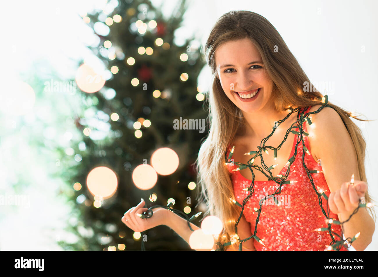 Porträt der jungen Frau schmücken Weihnachtsbaum mit Weihnachtsbeleuchtung Stockfoto