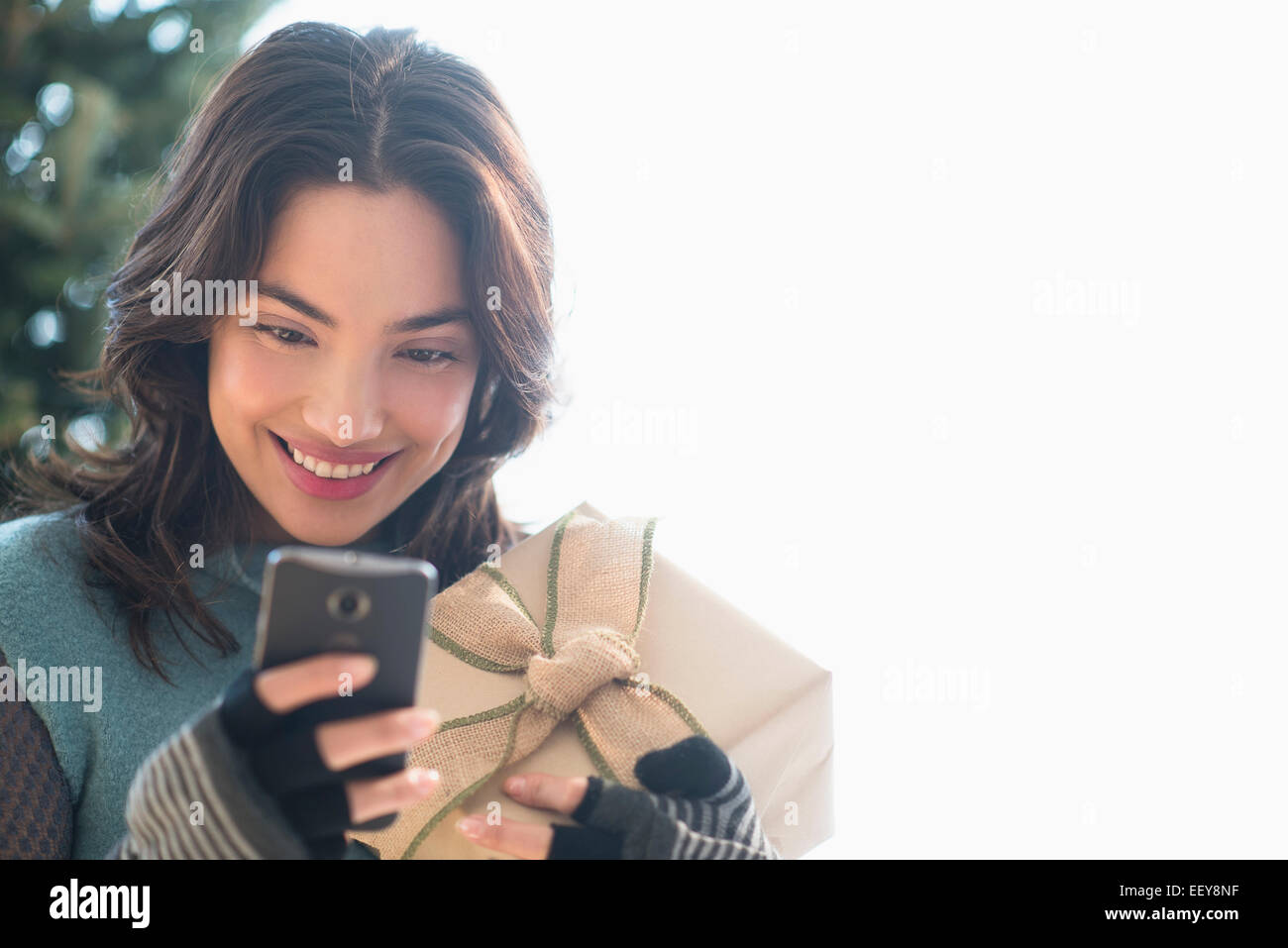 Lächelnde junge Frau mit Geschenk und Text-messaging Stockfoto