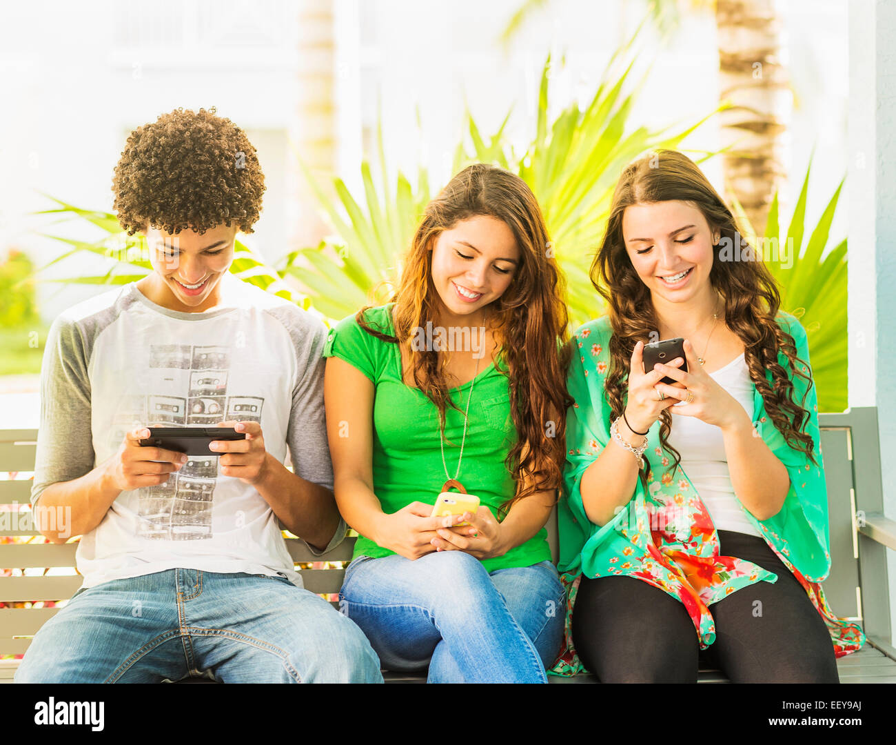 USA, Jupiter, Florida, Gruppe von Freunden (14-15) sitzen auf Bank und SMS Stockfoto
