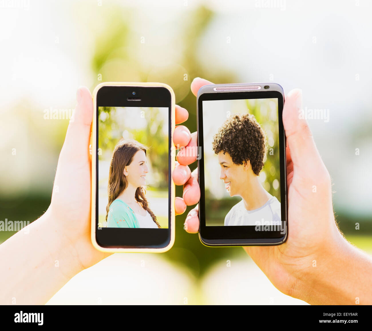 Mann und junges Mädchen (14-15) halten Smartphones mit Fotos von sich selbst Stockfoto