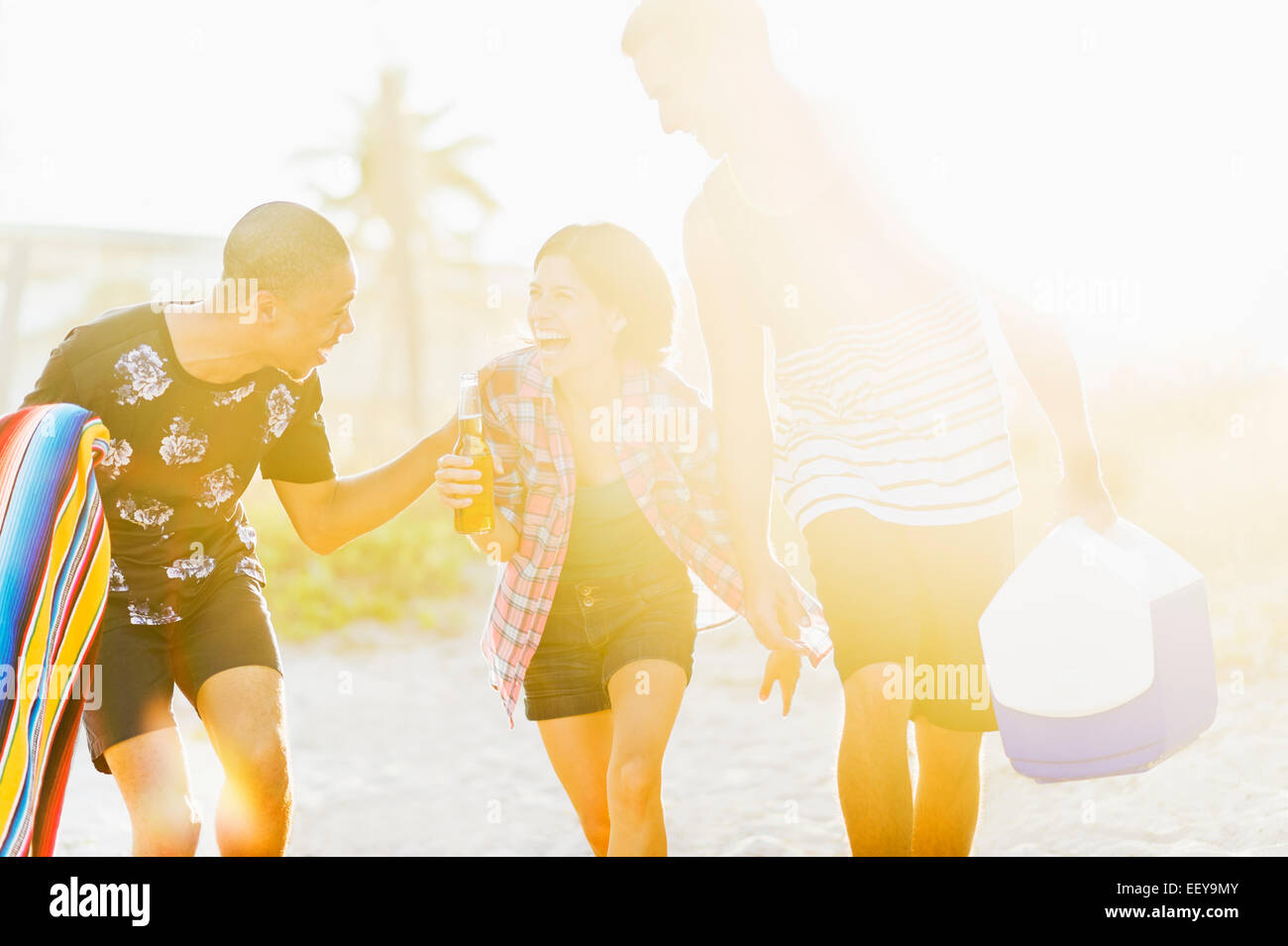 USA, Florida, Jupiter, junge Menschen zu Fuß am Strand, trinken Bier bei Sonnenuntergang Stockfoto