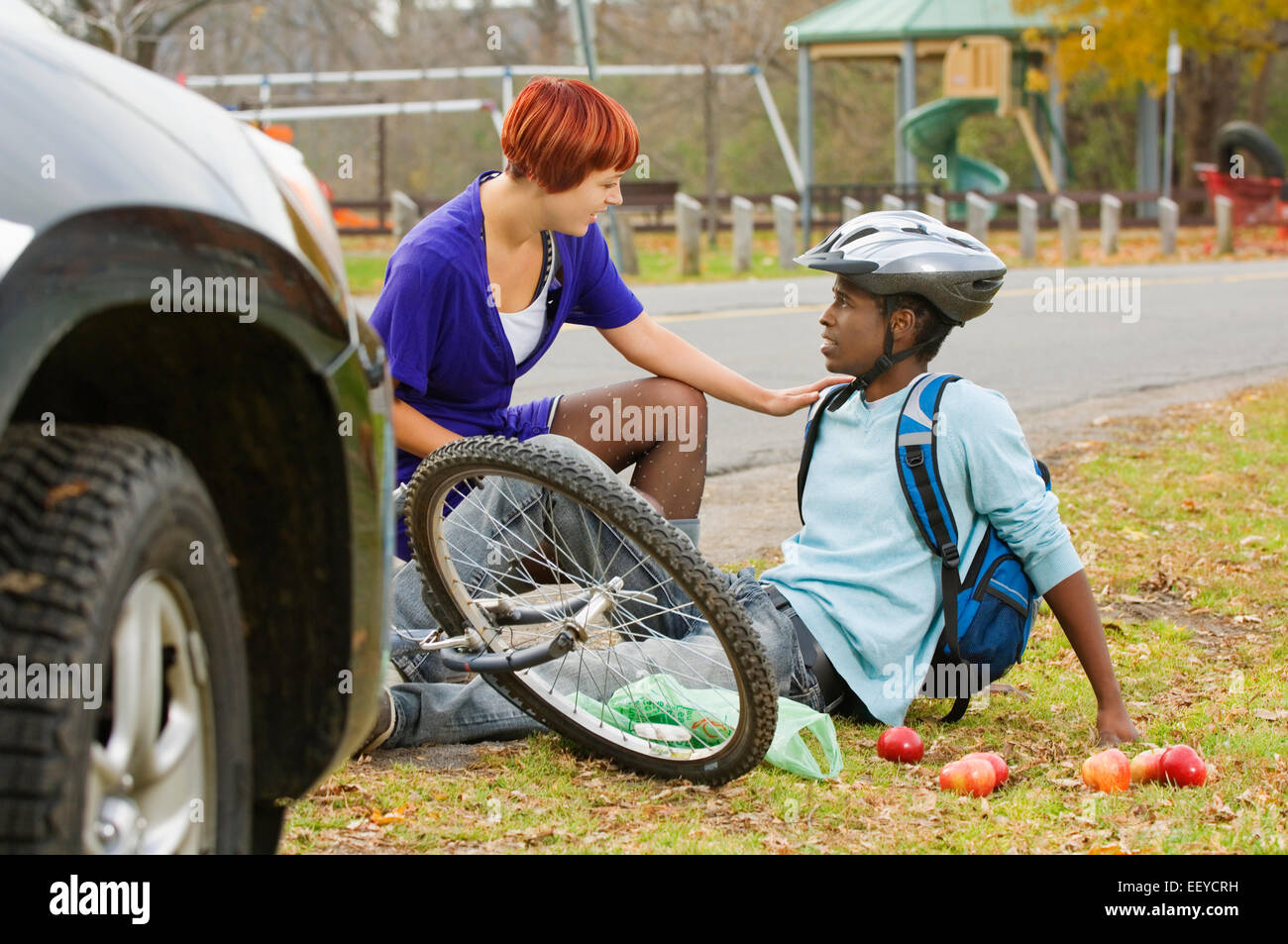 Radfahrer zu helfen, nachdem er von einem Auto angefahren wurde Frau Stockfoto