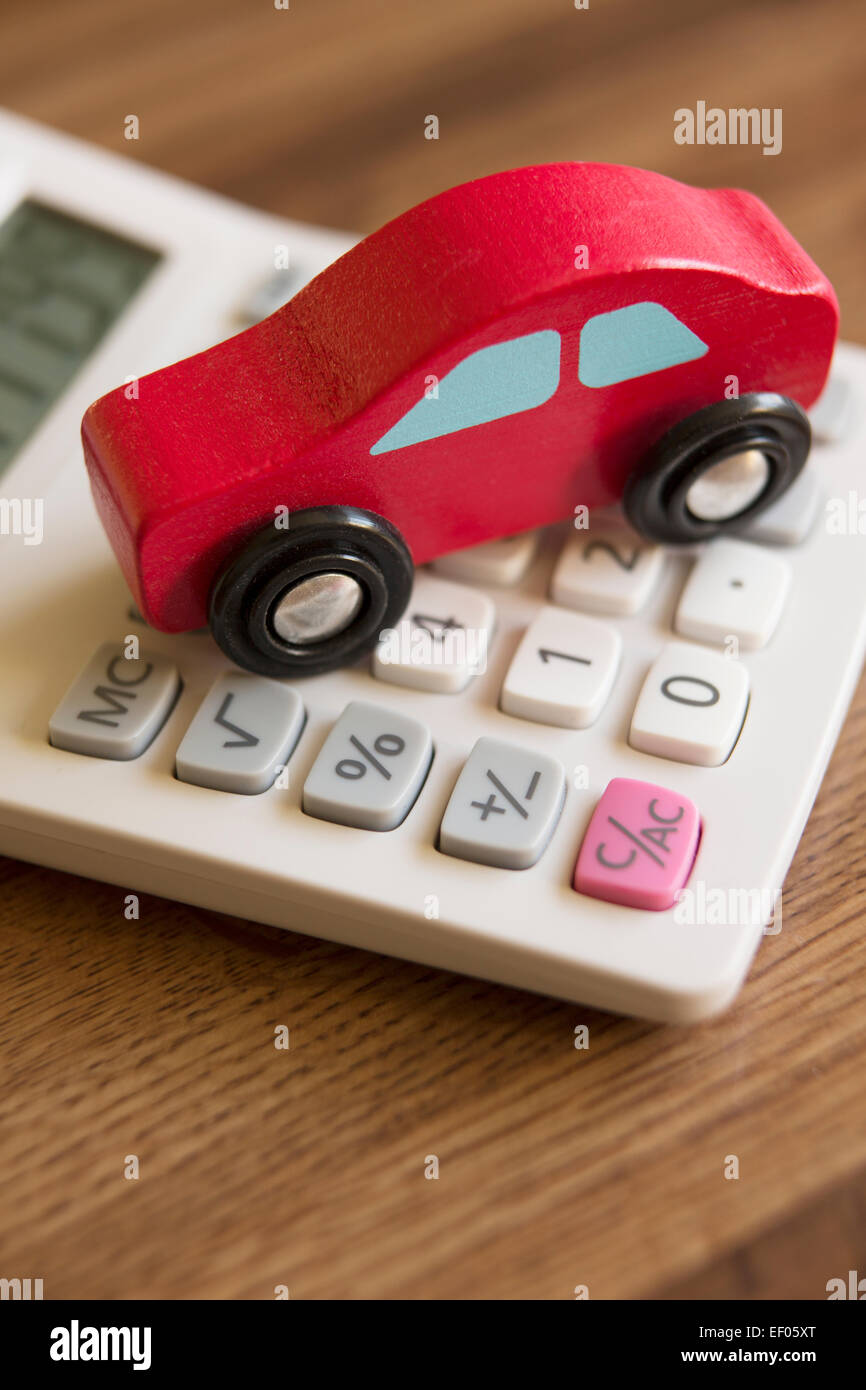 Rot aus Holz Spielzeugauto auf Rechner, um die Kosten des Autofahrens zu veranschaulichen Stockfoto