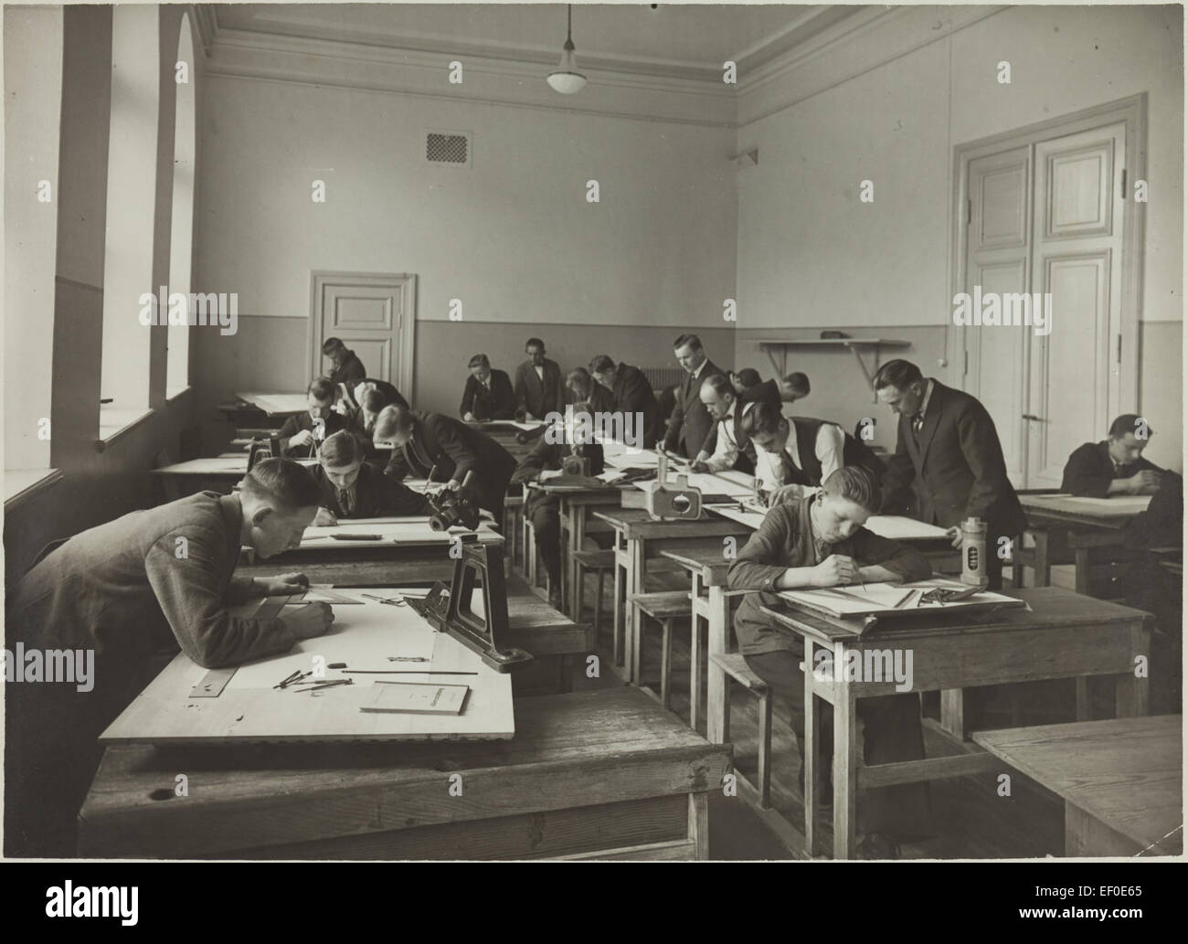 Dieses Bild zeigt die Teilnehmer an einem Kurs zum Zeichnen von Maschinen mit Schwerpunkt auf technischen Fähigkeiten für Industriedesign und Ingenieurwesen. Sie spiegelt die damaligen pädagogischen Praktiken wider. Stockfoto