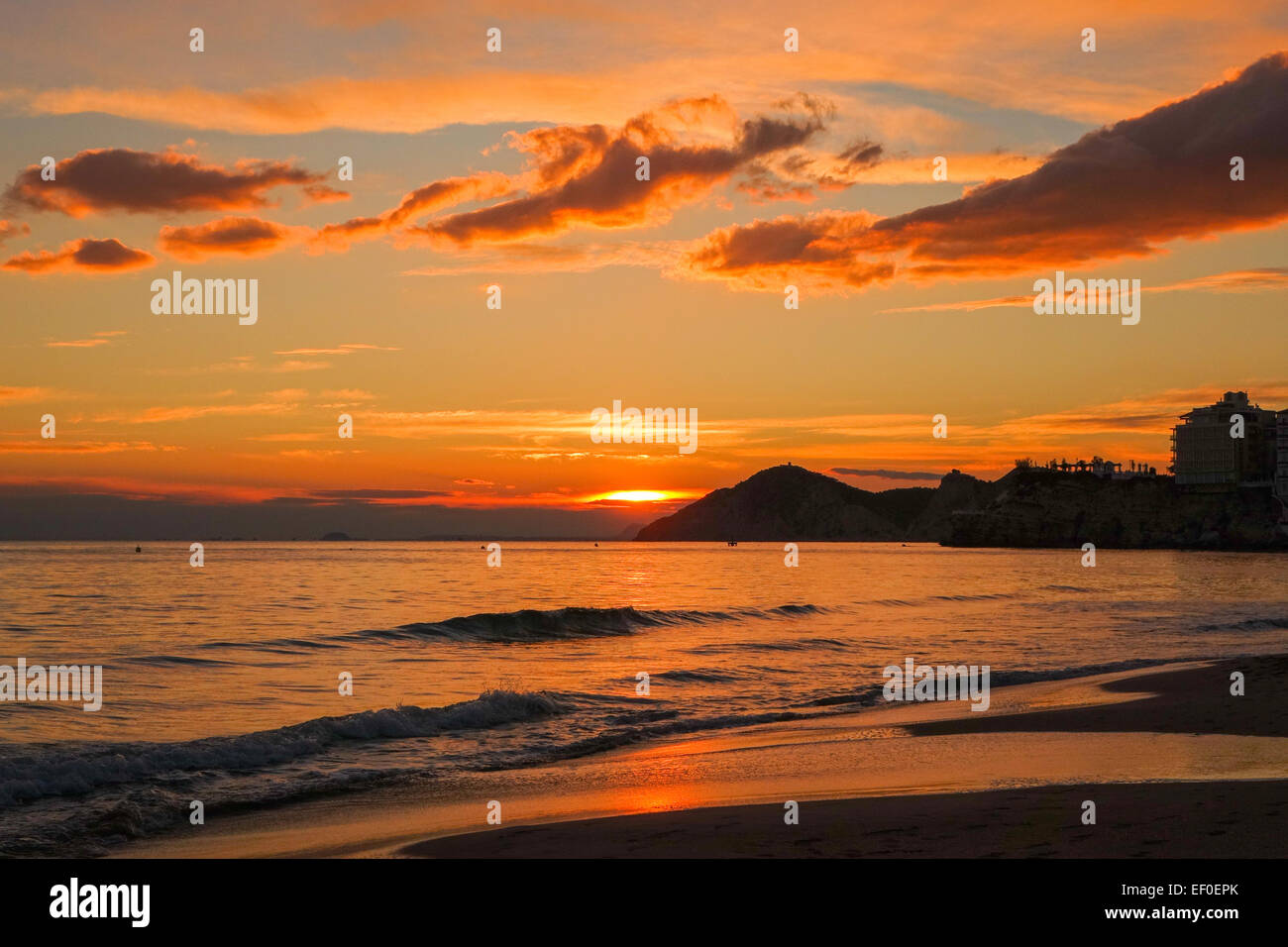 Benidorm-Sonnenuntergang, orange mit Meeressand und Wolken Stockfoto