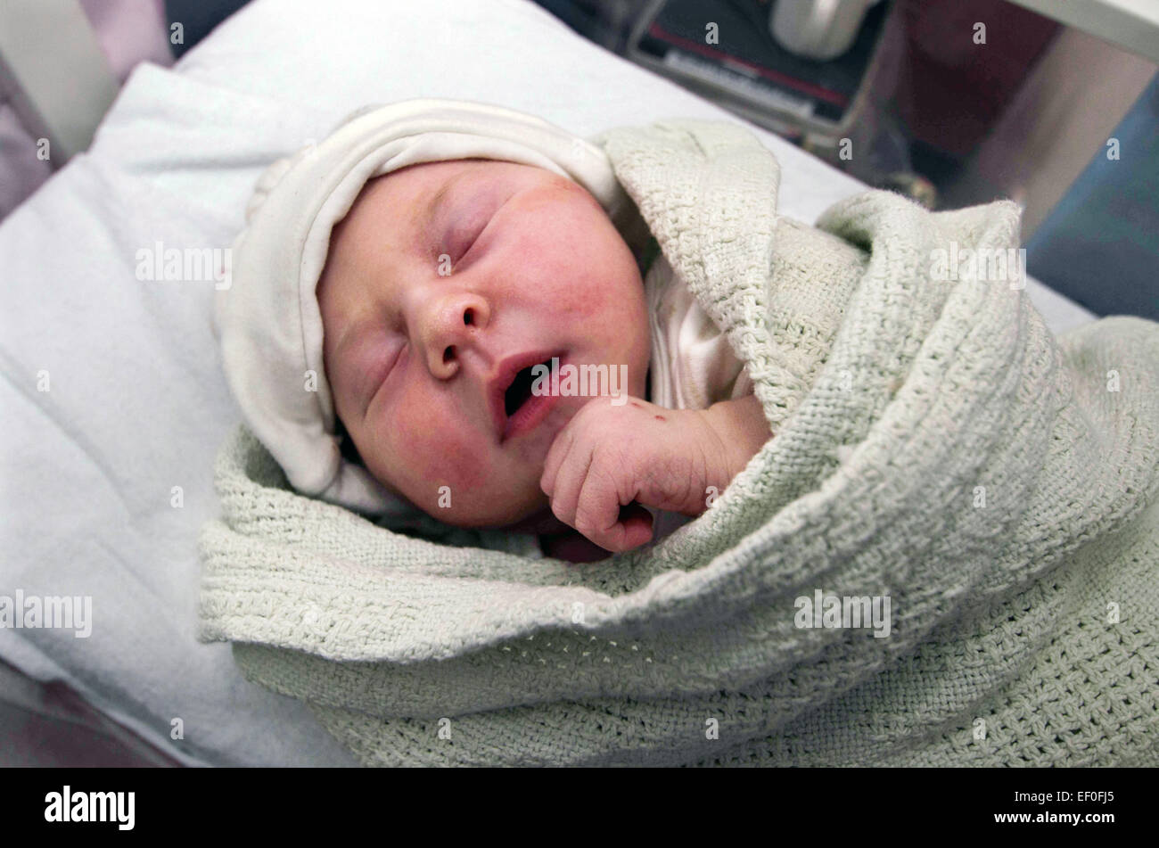Ein neugeborenes Baby fest eingewickelt in eine Decke schlafen im Kinderbett in Spitalabteilung. Stockfoto