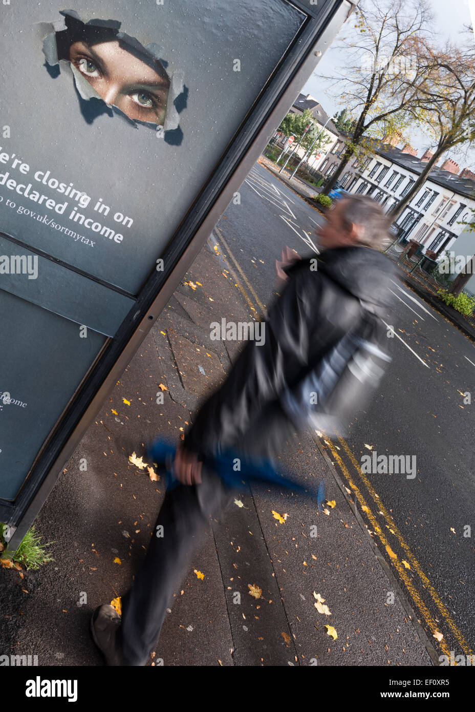 Ein paar Augen halten ein wachsames Auge auf die Aktivitäten der Straße von einer Telefonkabine aus als ein Fußgänger läuft durch. Stockfoto