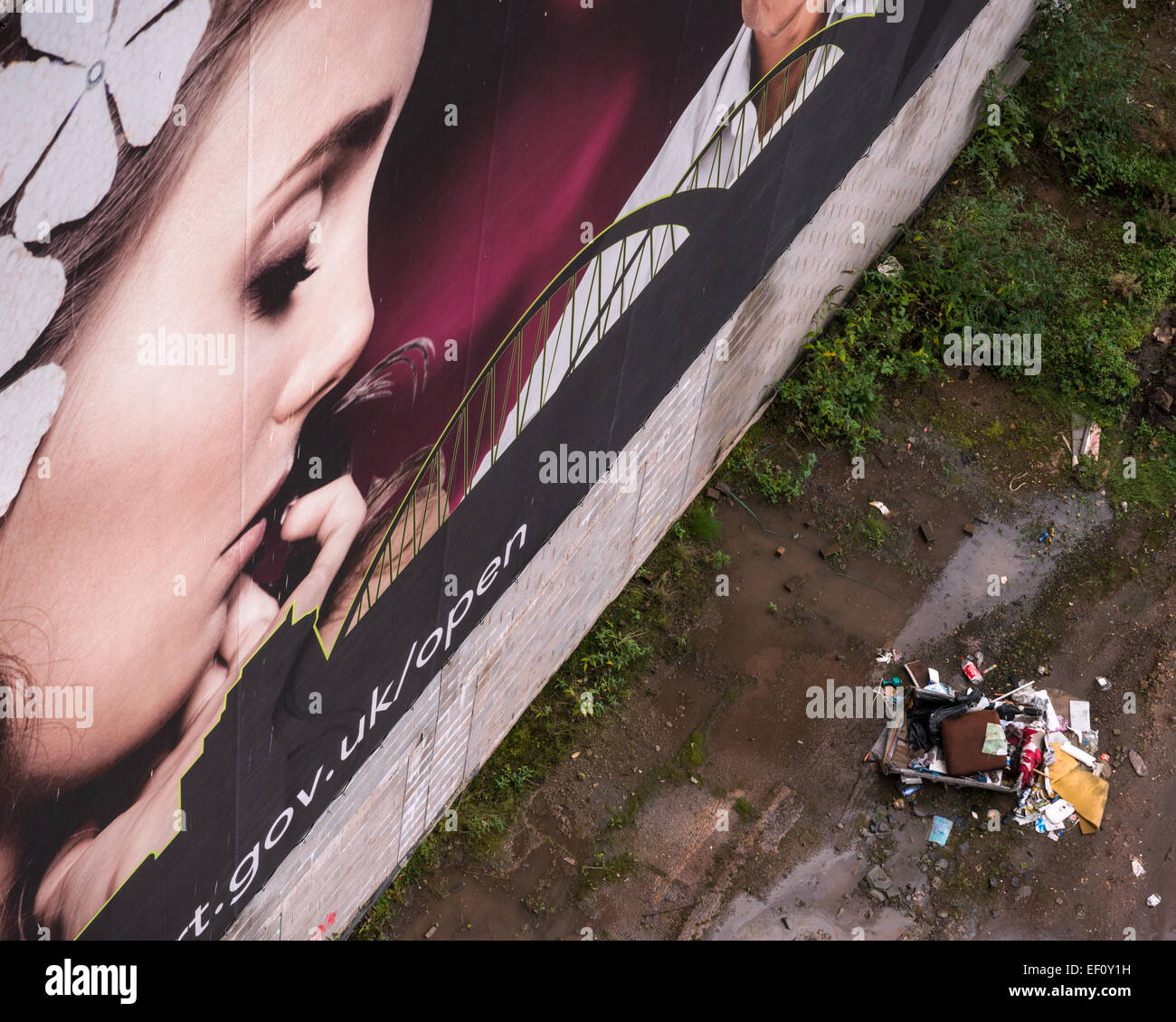 Eine Instanz des Fly tipping neben ein großes Banner mit einer schönen Dame blickte auf die Abfälle. Stockfoto