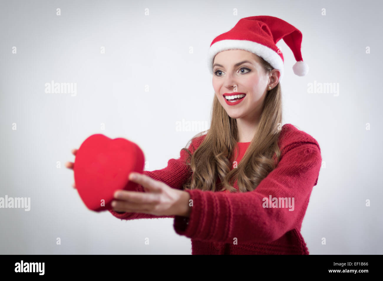 nette junge Frau mit Weihnachtsmann-Mütze und ein rotes Herz in einen weißen Hintergrund Stockfoto