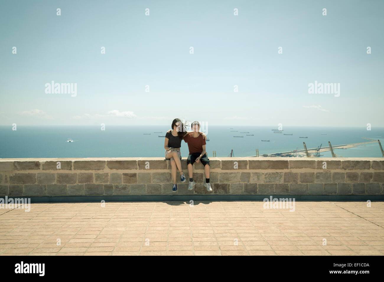 Castell de Montbejuic Barcelona, Schwester und Bruder auf einer Mauer sitzend Stockfoto