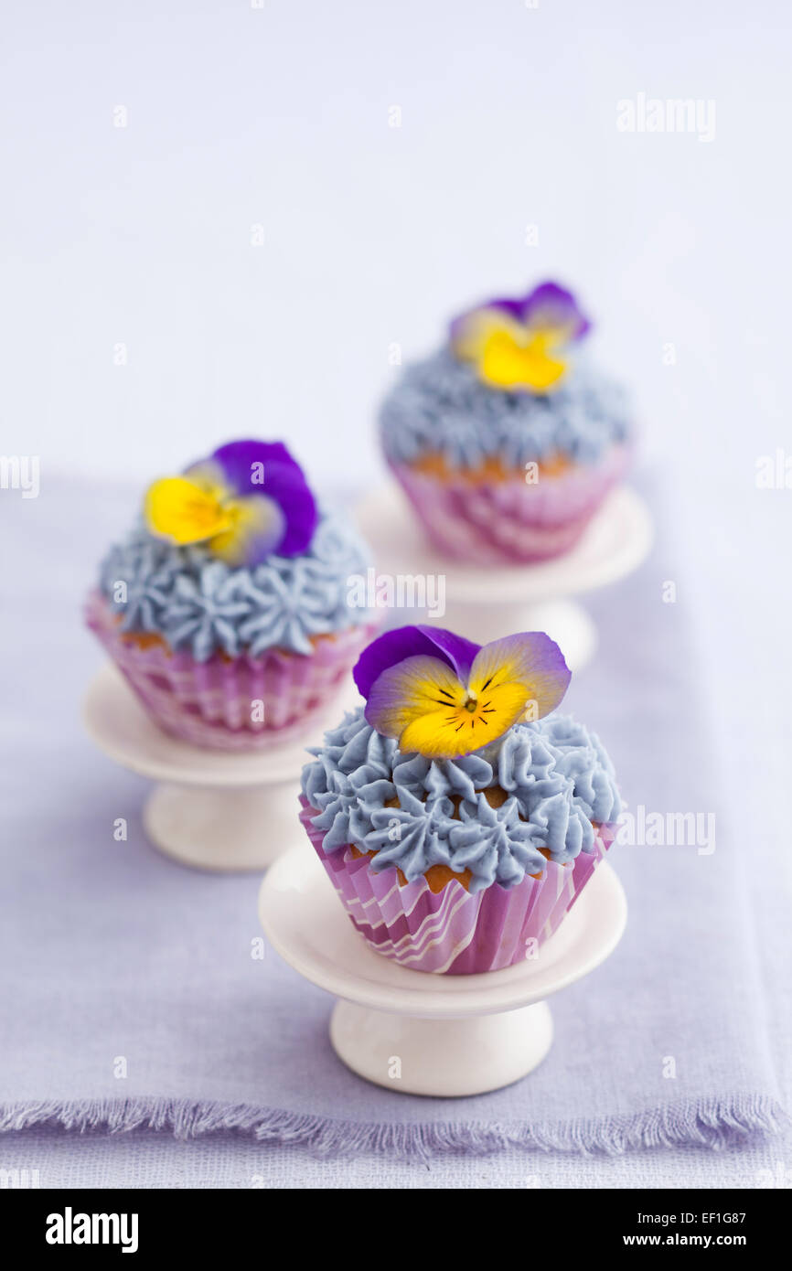 Drei Mini-Cupcakes mit Buttercreme topping und essbare Stiefmütterchen Stockfoto