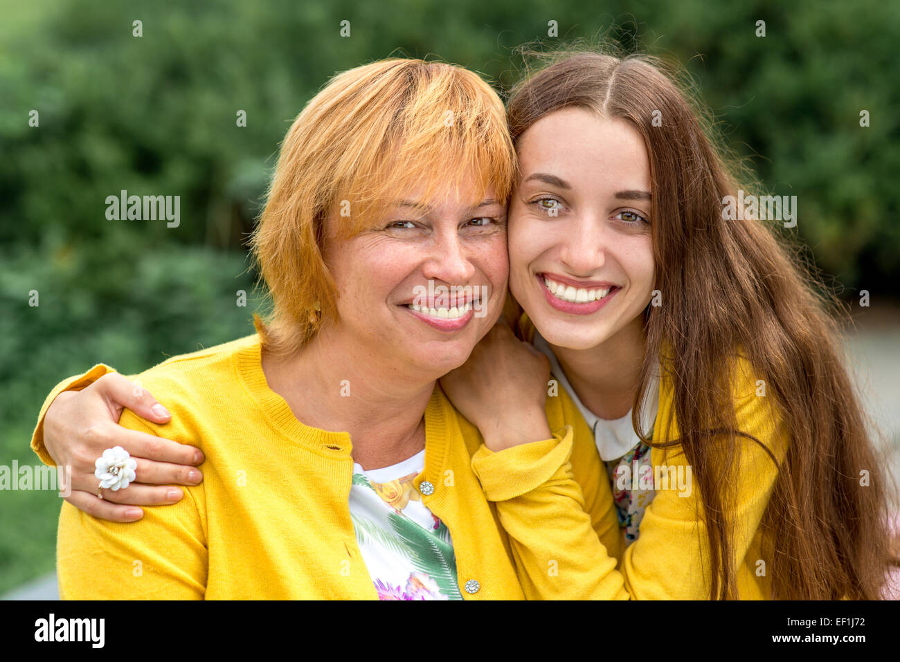Mutter mit ihrer Tochter Lächeln und Umarmungen gekleidet in gelb im park Stockfoto