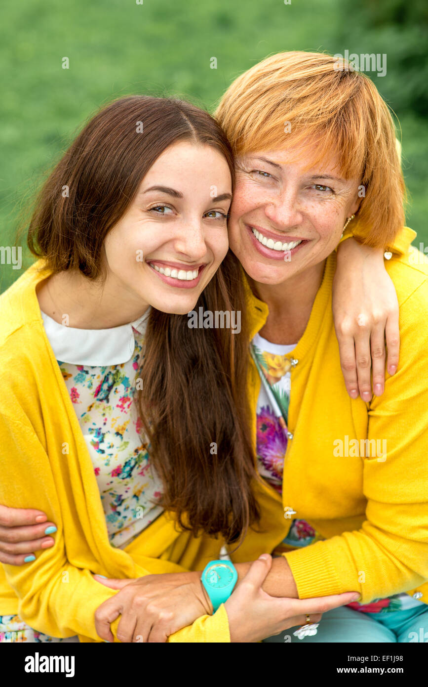 Mutter mit ihrer Tochter Lächeln und Umarmungen gekleidet in gelb im park Stockfoto
