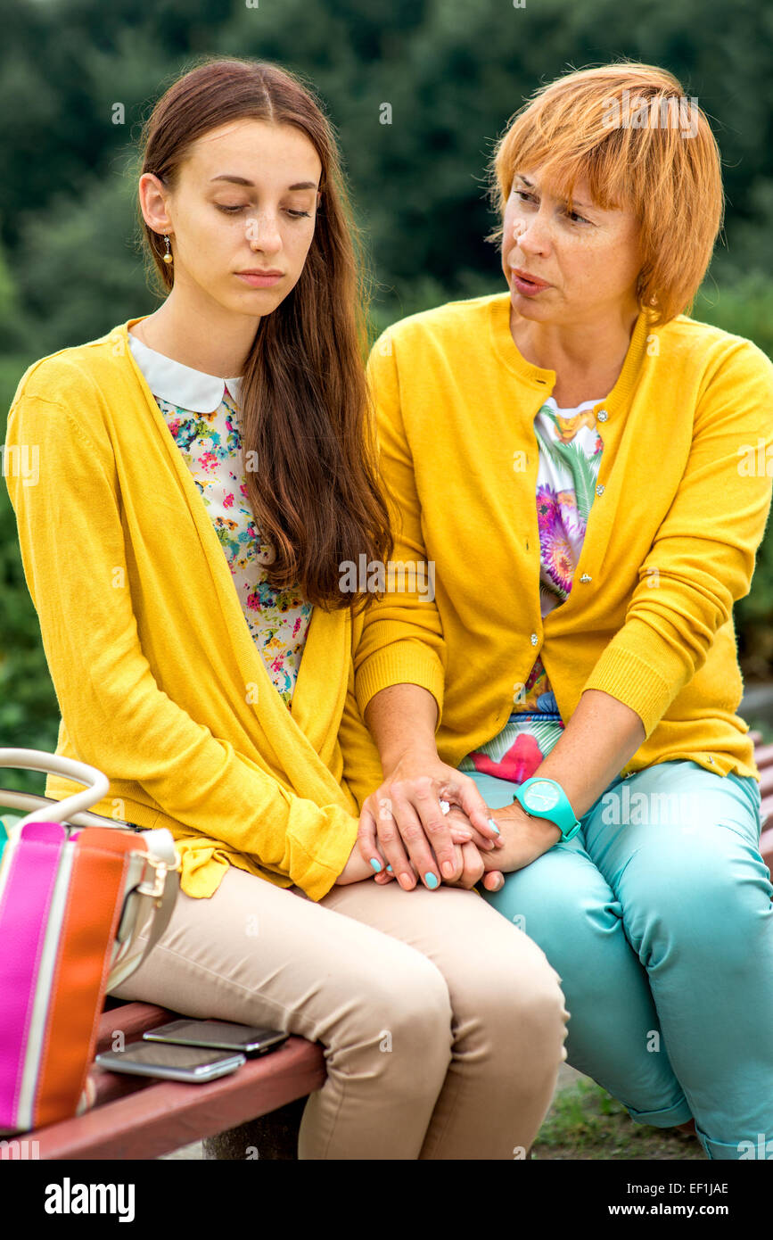 Mutter im Gespräch mit ihrer Tochter sitzt auf der Bank im park Stockfoto