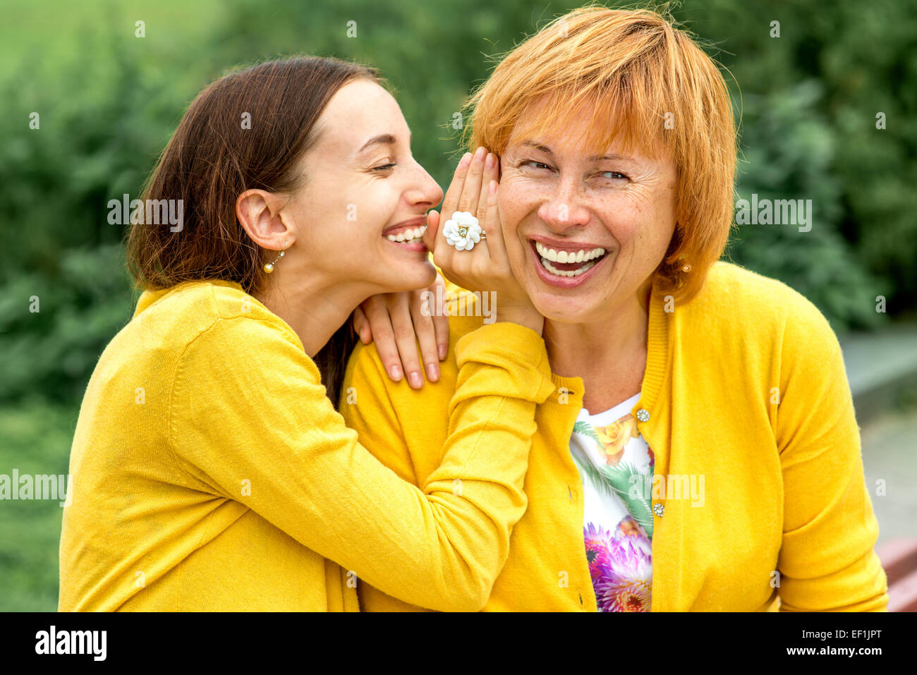 Tochter flüsterte etwas zu ihrer Mutter im park Stockfoto