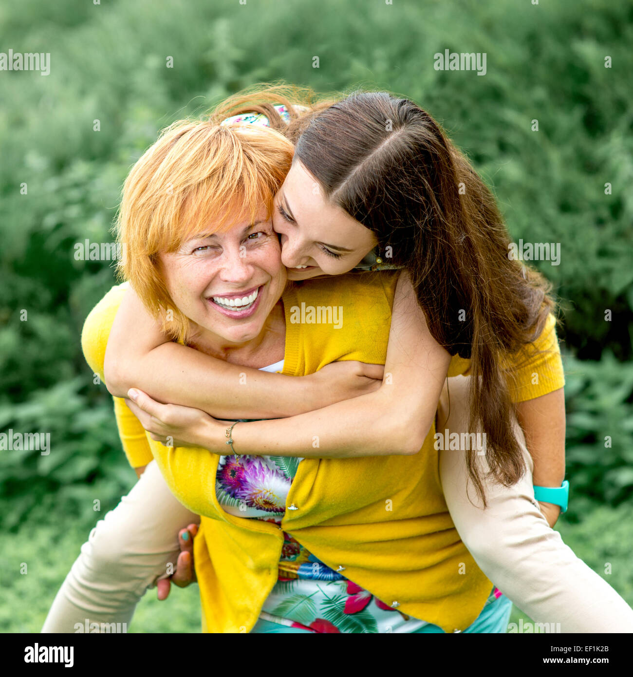 Mutter, Huckepack Reiten, ihre Tochter im park Stockfoto