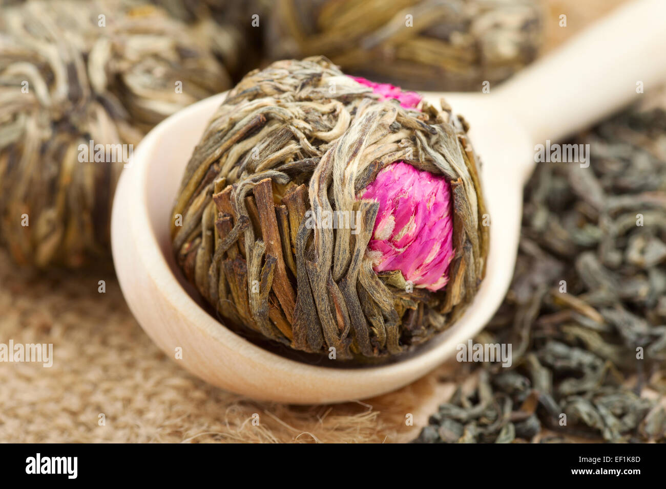 Grüner Tee-Ball mit Blumen in Holzlöffel und Tee Blätter Stockfoto