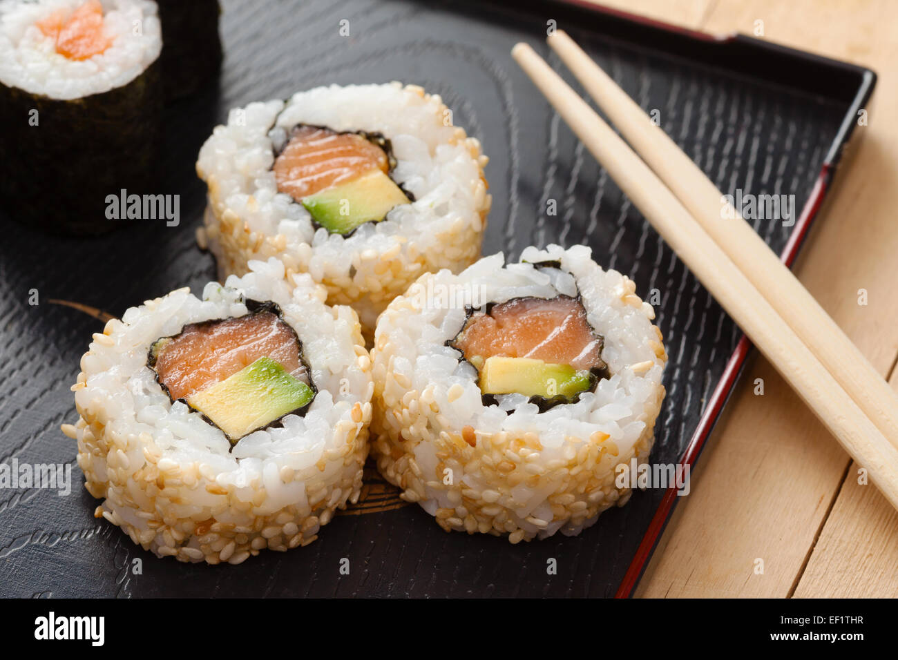 Sushi-Rollen Sortiment auf schwarze Platte und hölzerne Stäbchen Stockfoto