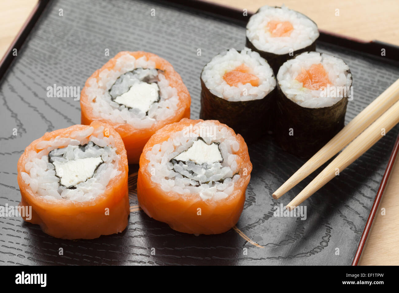 Sushi von Räucherlachs und Philadelphia Käse und Maki mit Stäbchen Stockfoto