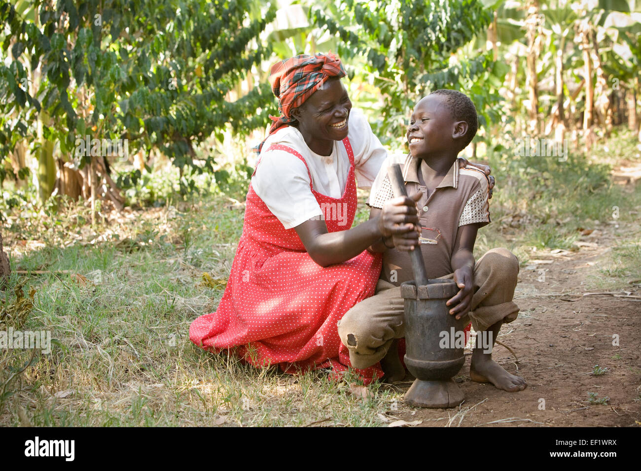 Mutter und Sohn verwenden einen Motor und Stößel in Buwanyanga Dorf - Sironko, östlichen Uganda, Ostafrika. Stockfoto