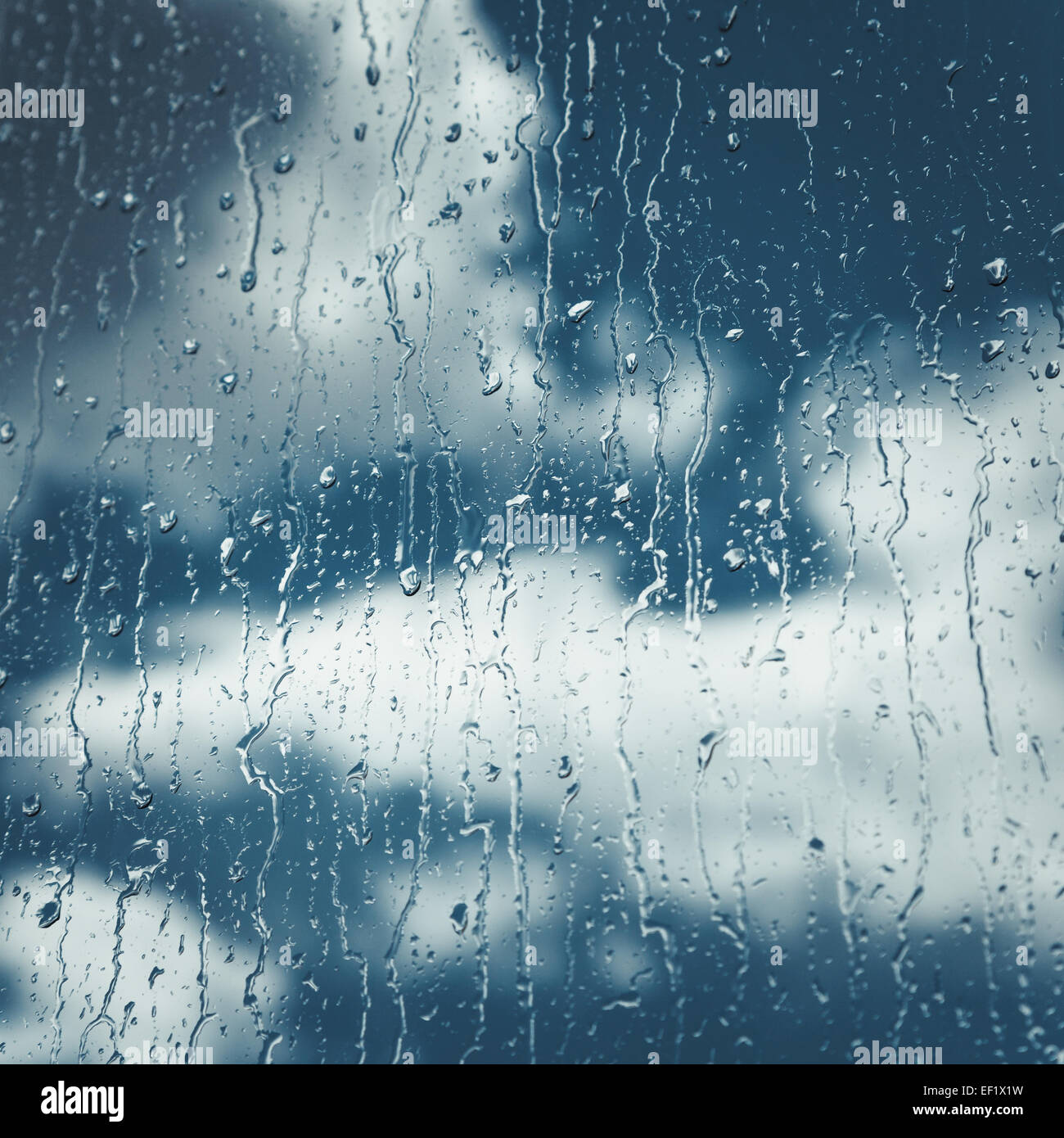Regen Tropfen und fließt am Fenster, blauer Himmel mit Wolken im Hintergrund Stockfoto