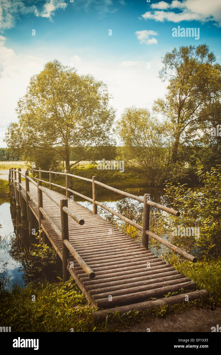 hölzerne Fußgängerbrücke über einen kleinen Fluss Stockfoto