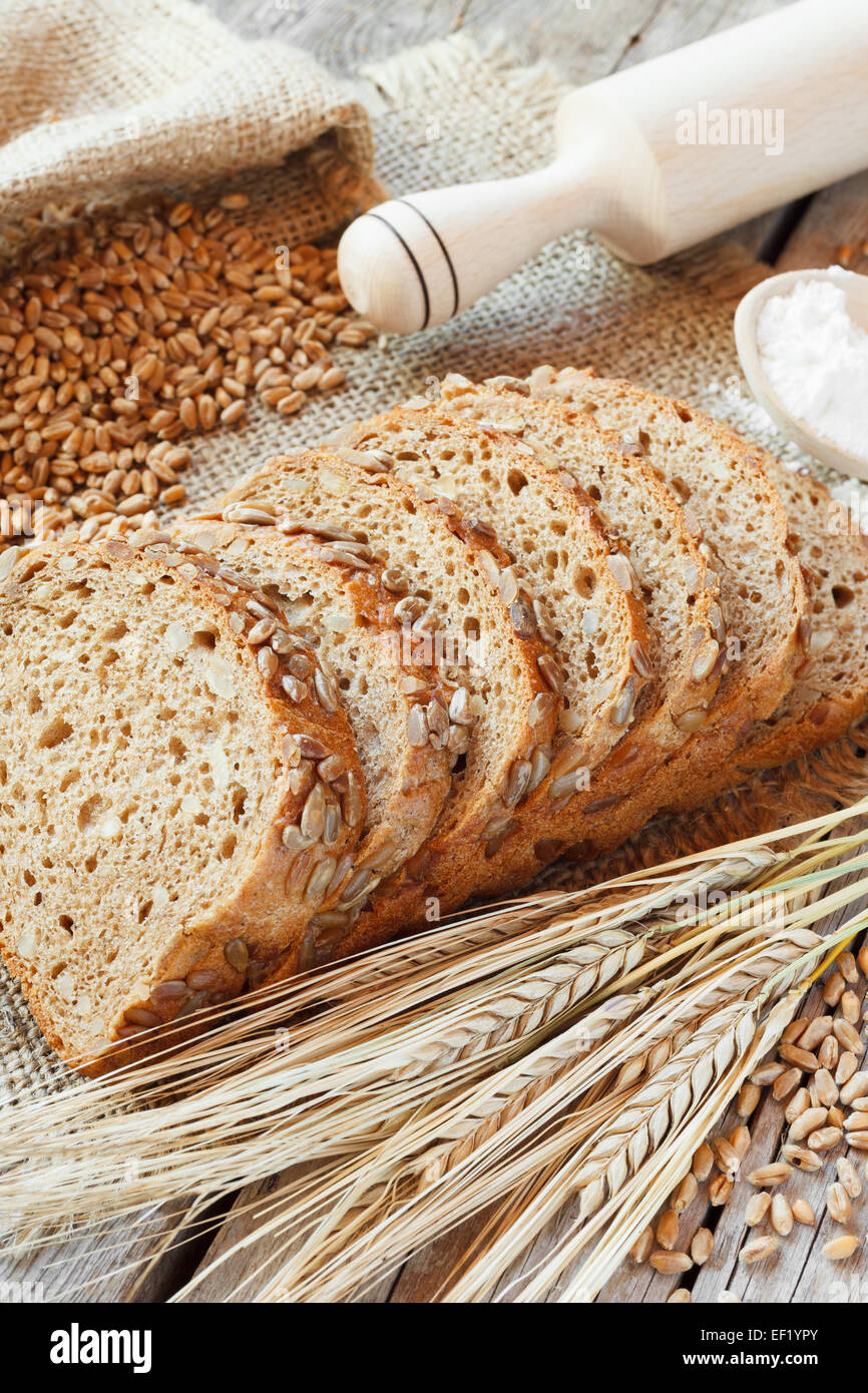Brot, Scheiben, Nudelholz, Korn und Roggen Ohren am Küchentisch Stockfoto